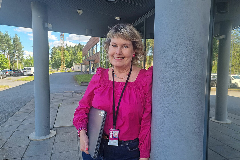 Satu nojaa TAKKin rakennuksen edustalla olevaan pylvääseen, kannettava tietokone kainalossaan.