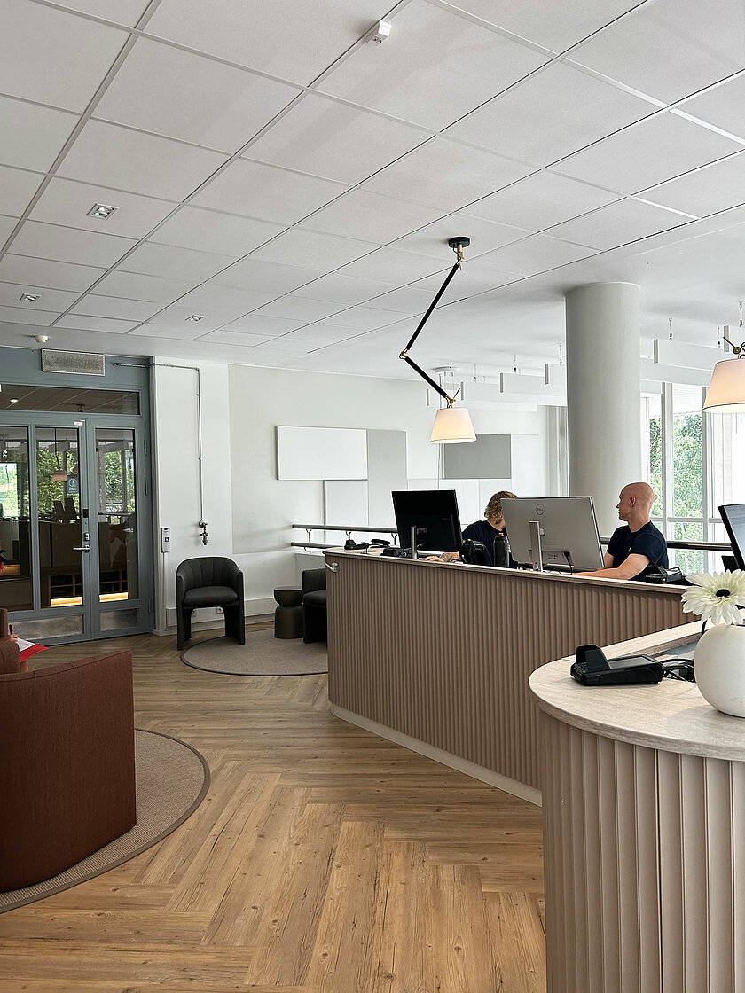 Urheiluhierojakoulun vastaanottotiski valoisassa aulassa. Tiskin takana kaksi opiskelijaa.