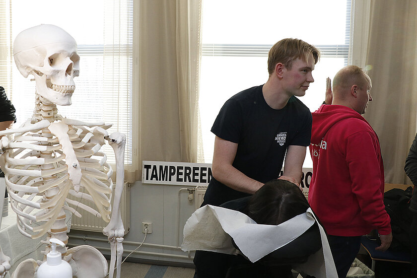 Luuranko ja henkilö hieromassa Loistoduuni-kävijän niskaa.