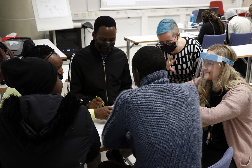 Kenialaisia opiskelijoita kahden kouluttajan kanssa pöydän ympärillä.