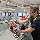 Kouluttaja työskentelee teollisuuskeittiön kylmälaitteiden parissa valoisassa harjoitustilassa.