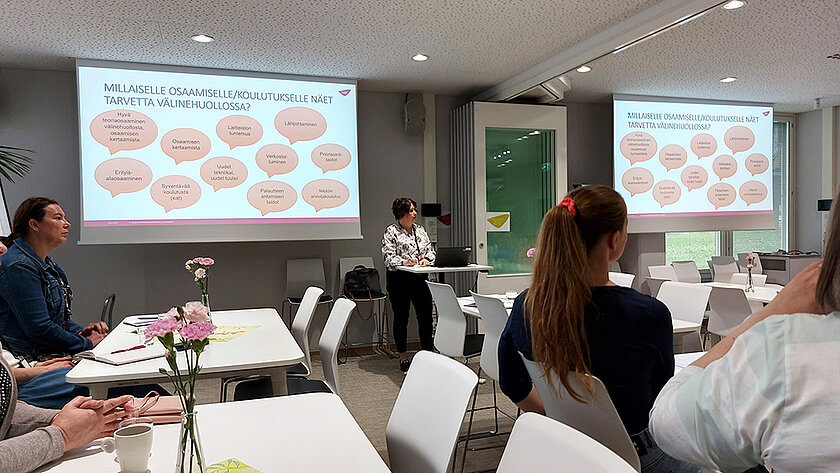 Henkilö puhuu, taustalle heijastettu välinehuoltoalalla tarvittavia osaamisia.