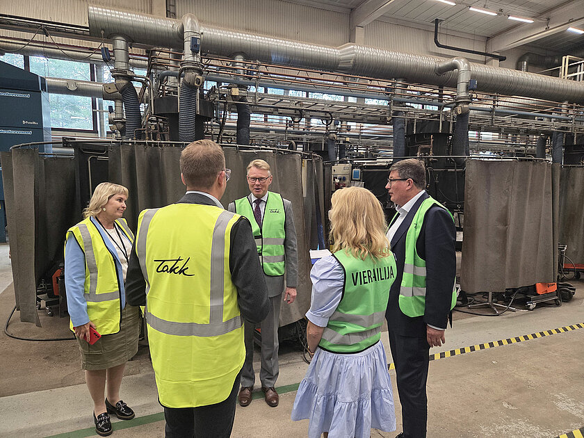 Huomioliiveihin pukeutuneet ihmiset TAKKin hitsausalan oppimisympäristössä keskustelemassa ringissä.