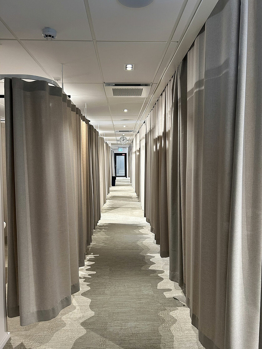 Käytävä, jonka molemmin puolin asiakastiloja verhojen takana.
