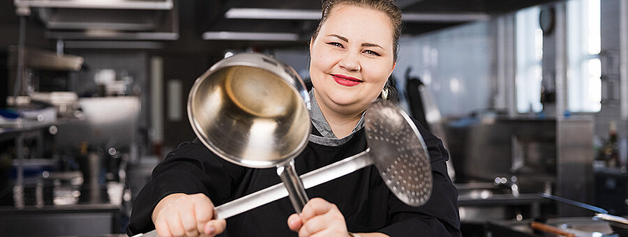 Kokki ravintolan keittiössä käsissään kaksi isoa kauhaa.