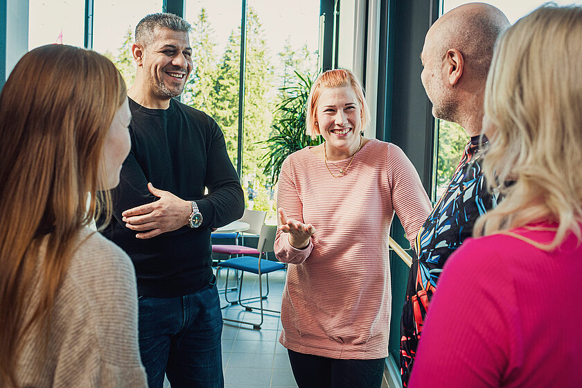 Neljä henkilöä keskustelee iloisesti TAKKin sisätiloissa.