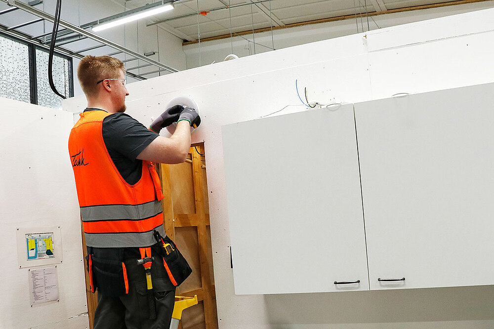 Sähköalan opiskelija valaisimen asennusharjoituksessa Sähkövalaisimen asennusharjoitus