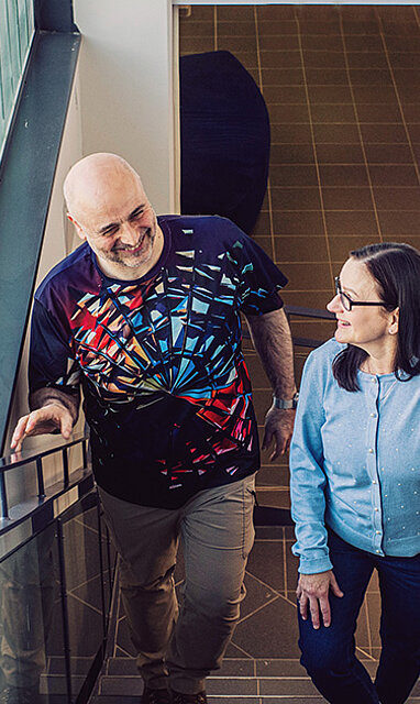 Kaksi ihmistä nousemassa portaita keskustellen yhdessä.