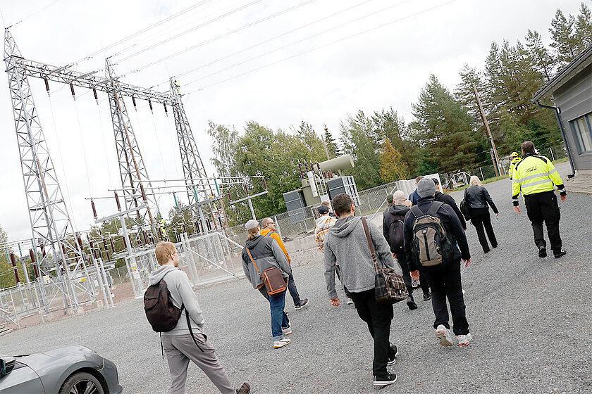 Ryhmä ihmisiä kävelee taustalla näkyvää sähkökenttää kohti.
