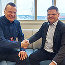 Rehtorit Teppo Tapani ja Jarno Tuimala istuvat suuren ikkunan edustalla sohvalla ja kättelevät.