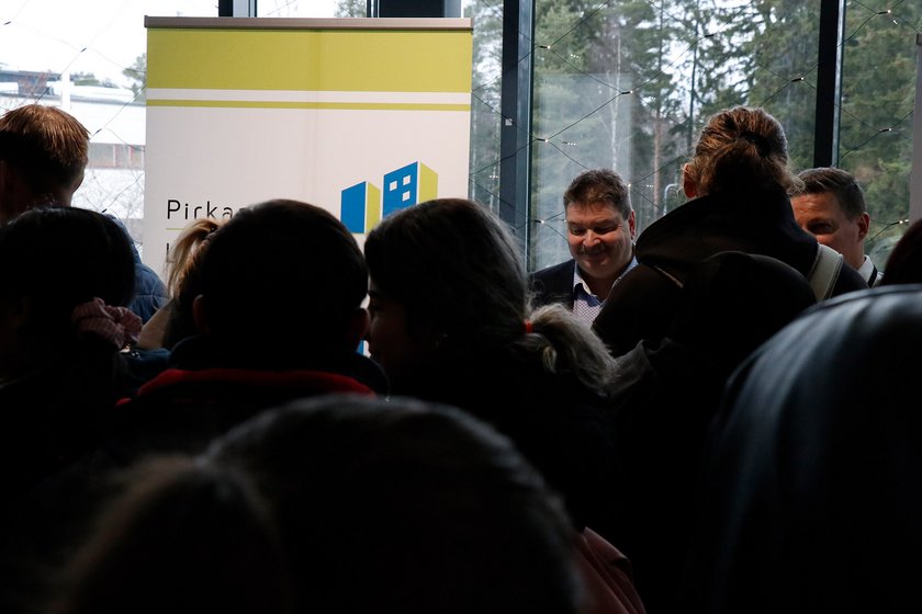 Suuren ihmismassan takaa näkyy hymyilevä pää.