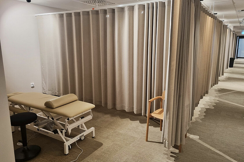 Yksi Urheiluhierojakoulun hierontapisteistä beigen sävyisten verhojen ympäröimänä.