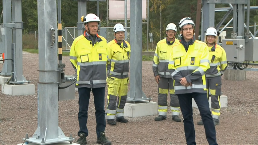 Rehtori Teppo Tapani, opetusneuvos Jukka Lehtinen ja kolme sähköverkkoalan kouluttajaa seisovat sähköpylväiden vieressä.