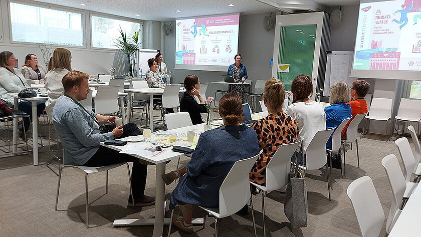 Välinehuoltoalan yhteistyöfoorumin osallistujia istumassa ja seuraamassa esitystä.