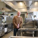 Tapio is standing in the middle of kitchen, where the students learn to cook.