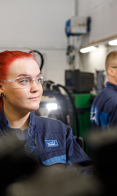 Kaksi henkilöä hydrauliikkalaitteiden kanssa työhaalarit ja suojalasit päällä.