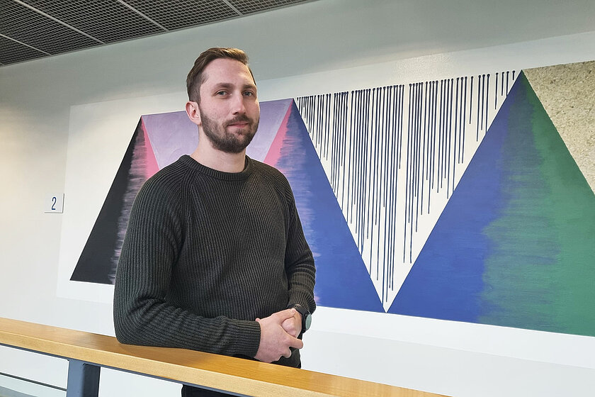 Jimi nojaa kaiteeseen, taustalla seinään maalattu kolmioita.