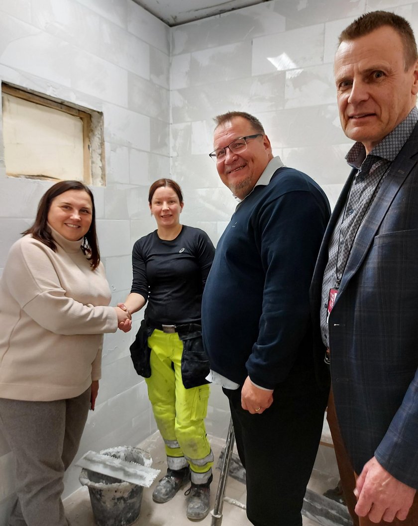 Kaksi miestä ja kaksi naista laatoitusharjoittelukopissa katsoo hymyillen kameraan.