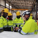 Viisi henkilöä työvaatteissa kypärät päässä.
