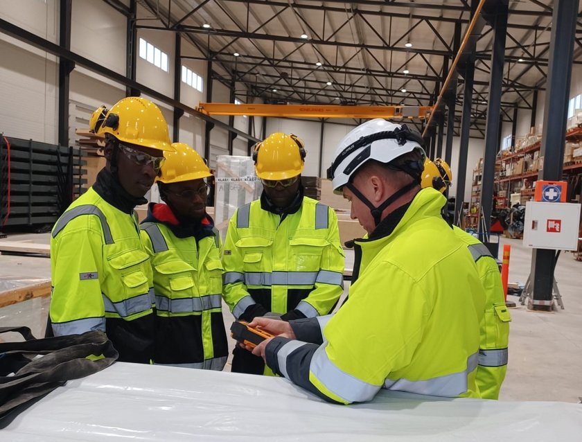 Viisi henkilöä työvaatteissa kypärät päässä.