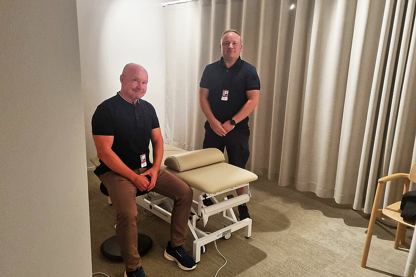 Tapio Määttänen ja Markus Kuusijoensuu urheiluhierojakoulun uusissa tiloissa hierontapöydän ympärillä, verhoseinän edessä.