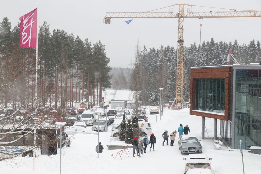 Bussikuljetuksella saapuneet kävijät kävelevät TAKKin parkkipaikan halki lumisateessa.