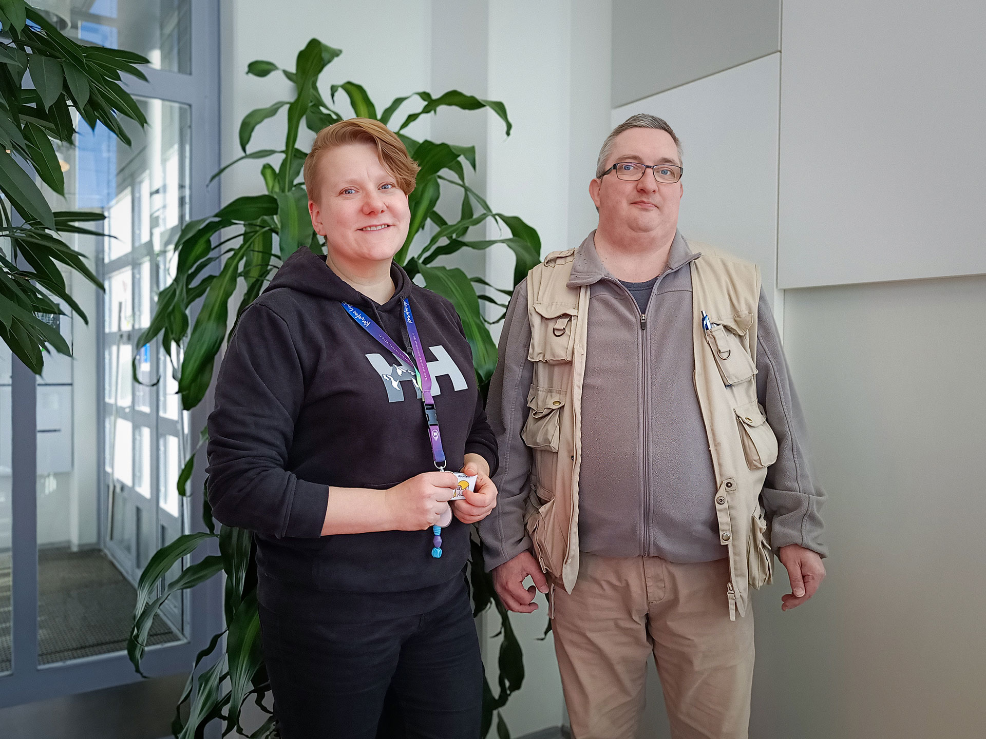 Minna ja Jussi seisoskelevat vieretysten viherkasvin edustalla TAKKin Tampereen valtatien kampuksella.