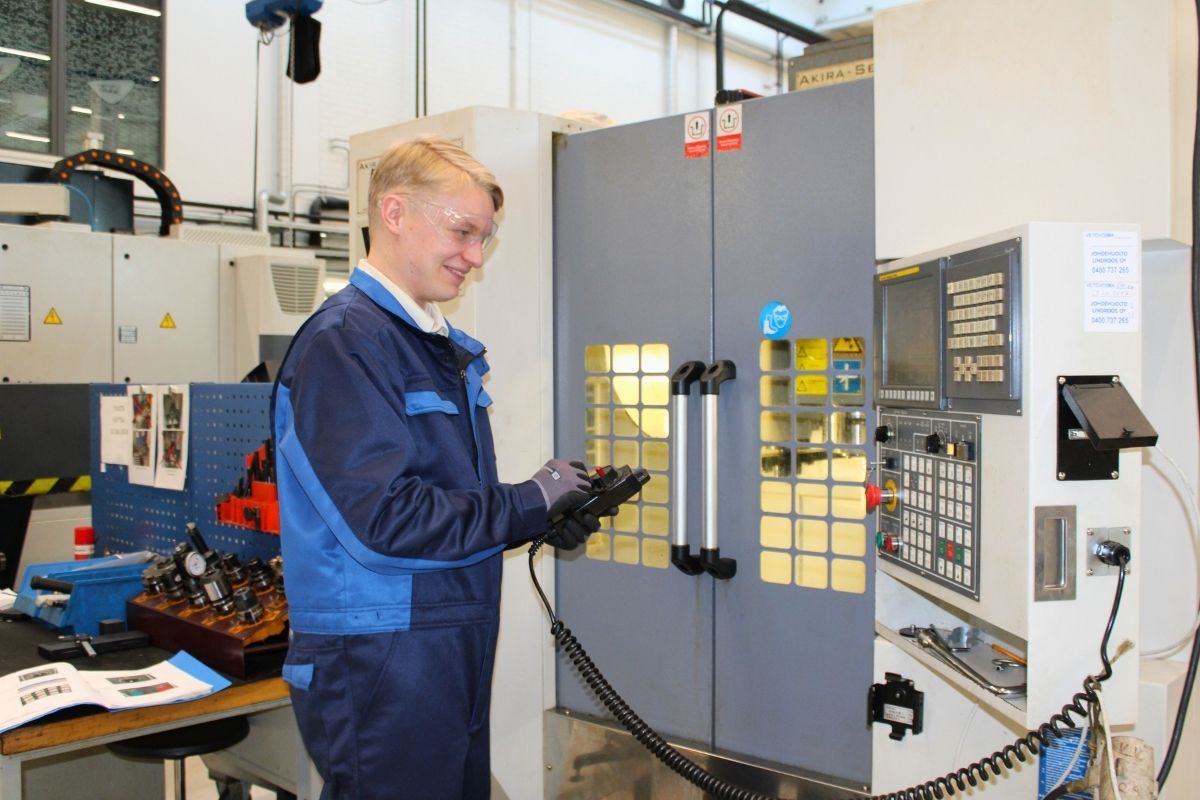 Lauri Kemppi Tampereen Aikuiskoulutuskeskuksen koneistushallissa sinen työhaalari päällään, suojalasit kasvoilla.