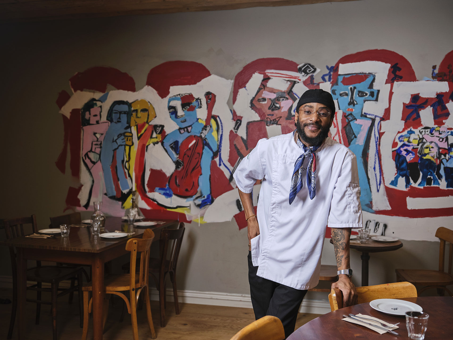 Ravintola-alaa opiskellut Jackson nojailee ravintolapöydän ääressä olevaan tuoliin, takanaan värikäs taideteos.