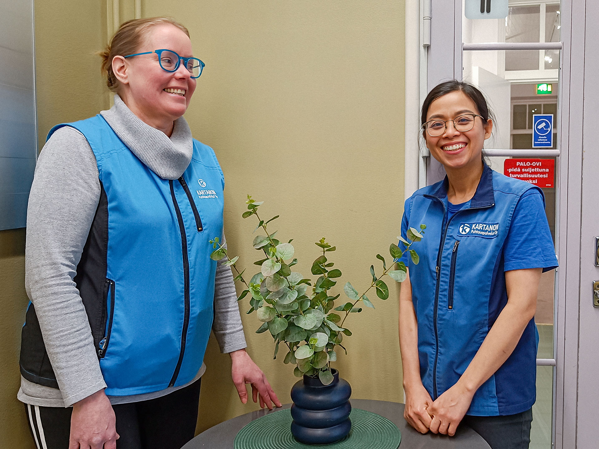 Sinisiin pukeutuneet Piia ja Loan hymyilevät pöydän ääressä.