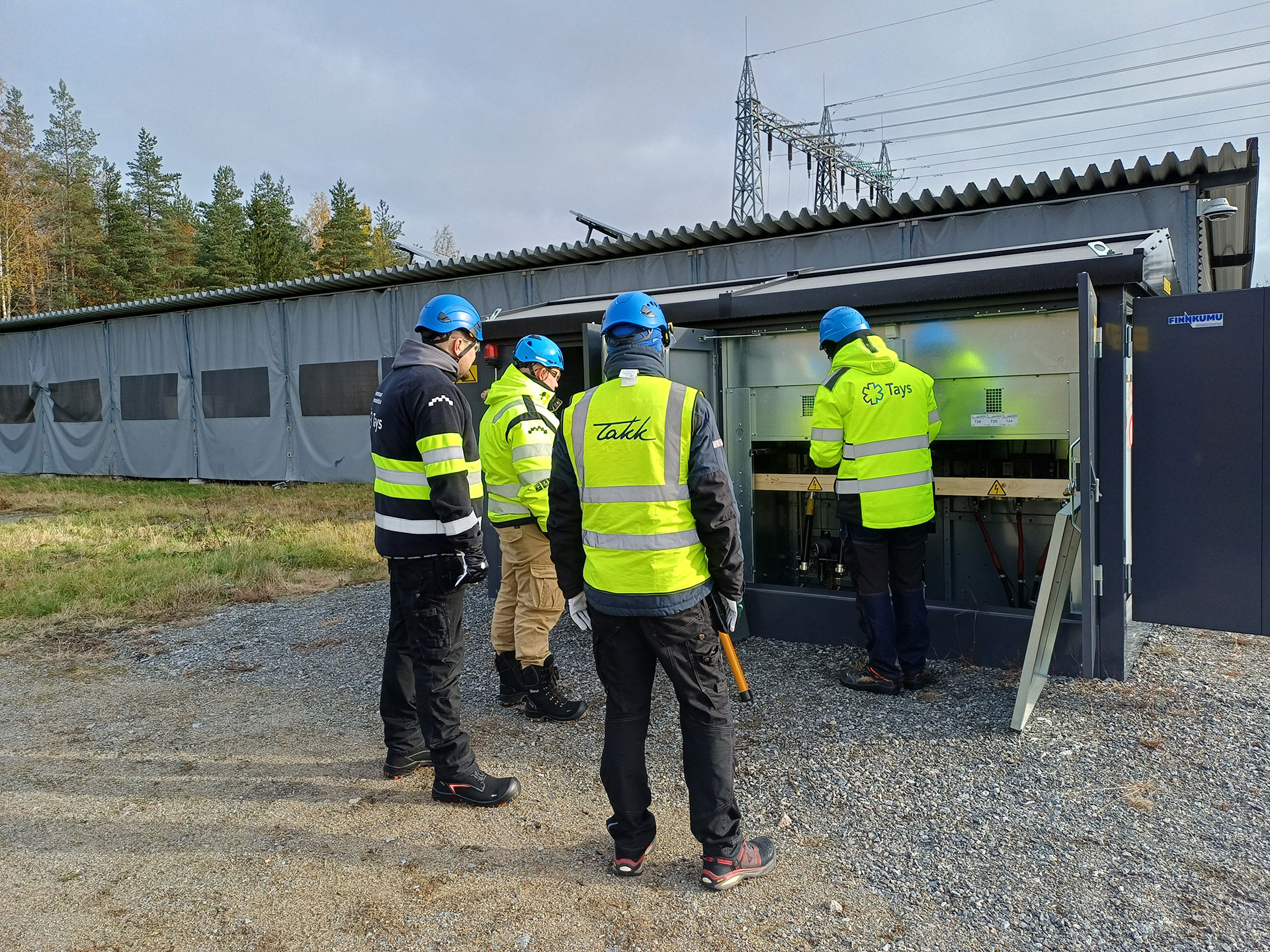 Työvaatteisiin pukeutuneet sähköalan ammattilaiset TAKKin sähkökentällä.