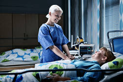 Lähihoitaja hoitamassa vuoteessa olevaa potilasta.